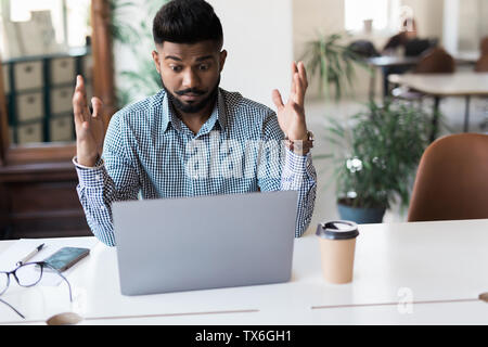 Homme d'affaires indien en colère crier sur laptop in office. Banque D'Images