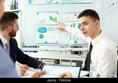 Smiling handsome man in office de dire quelque chose d'important pendant l'affichage d'informations sur tableau blanc headshot Banque D'Images