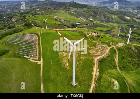 Paysage verdoyant paisible avec plusieurs Éoliennes et panneaux solaires sur le terrain avec des routes de campagne sur les collines en arrière-plan de l'Italie. Il y a des truck Banque D'Images