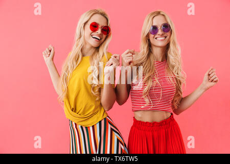 Photo de jumeaux en blonde heureux lunettes de s'amuser et danser sur fond rose Banque D'Images