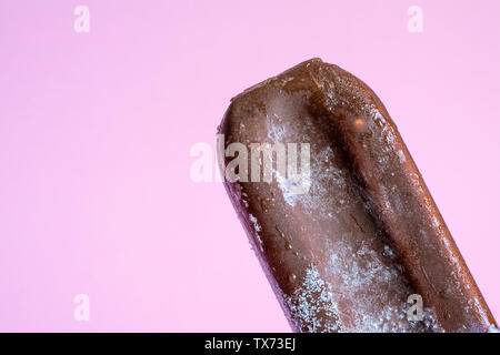 Lolly glaces en lustre de chocolat close-up avec le gel des condensats et du givrage sur un fond rose. Banque D'Images
