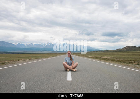 Femme assise sur la route Banque D'Images