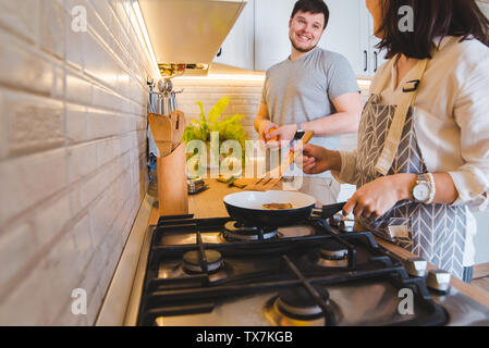 Couple cooking ensemble à la cuisine. faire frire les crêpes orange coupe de vie domestique. Banque D'Images