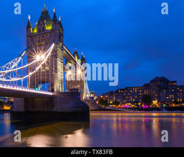 Londres, Royaume-Uni - 19 juin 2019 : les sentiers de la lumière d'un bateau passant sous le magnifique Tower Bridge, à Londres, au Royaume-Uni. Banque D'Images