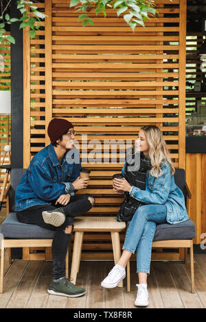 Multhiethnic sititng Smiling couple au café en plein air, de boire du café, à discuter Banque D'Images