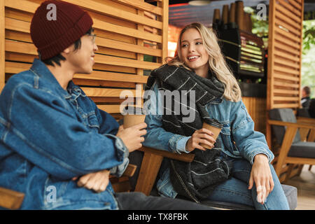 Multhiethnic sititng Smiling couple au café en plein air, de boire du café, à discuter Banque D'Images