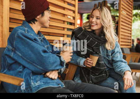 Multhiethnic sititng Smiling couple au café en plein air, de boire du café, à discuter Banque D'Images