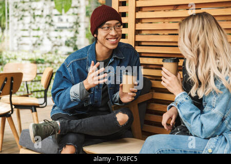 Multhiethnic sititng Smiling couple au café en plein air, de boire du café, à discuter Banque D'Images