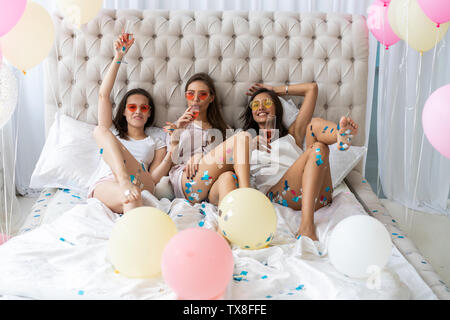 Soirée pyjama. Young smiling women in pyjamas drinking champagne tout en ayant un pyjama dans la chambre à coucher Banque D'Images