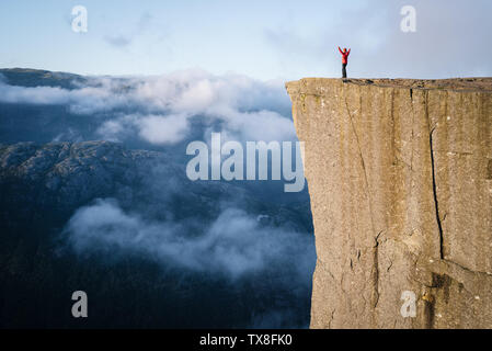 Preikestolen - incroyable rock en Norvège. Fille debout sur une falaise au-dessus des nuages. Pulpit Rock, la plus célèbre attraction touristique à Ryfylke, tours o Banque D'Images