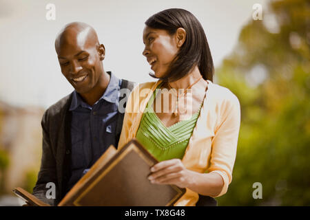 Jeune couple rire qu'ils en ont l'air à travers un album photo. Banque D'Images