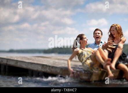 Trois amis à jouer tout en trempant les pieds dans l'eau. Banque D'Images