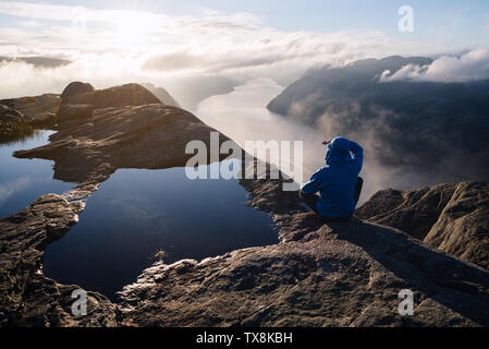 Près de Preikestolen (Pulpit Rock), la célèbre attraction touristique à Ryfylke, domine le Lysefjord. Guy sur un rocher regarde au loin et bénéficie d Banque D'Images