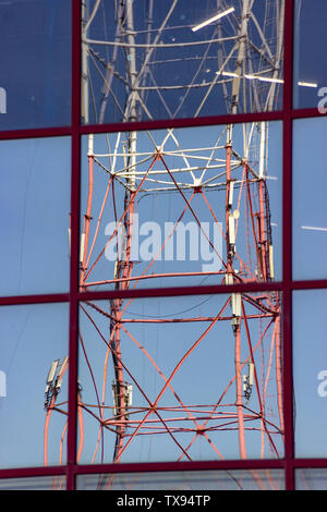 Reflet de la tour de transmission de radio avec des antennes de communication cellulaire dans la fenêtre miroir de bâtiment. L'internet mobile. Propagation de la déficience auditive s'haut Banque D'Images