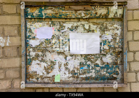 Wooden notice board sur un mur en brique blanche. Vieux bois peint avec des morceaux de papier. Papier blanc pour la publicité. Modèle de conception de la maquette. Spa de copie Banque D'Images