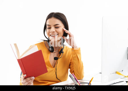 Portrait of Pretty woman hotline sous casque microphone lecture livre alors que working in office Banque D'Images