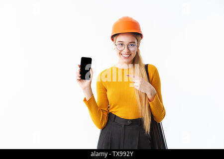 Attractive young woman architect isolés sur fond blanc, exerçant son activité sous tube, talking on mobile phone, montrant blak écran téléphone mobile Banque D'Images