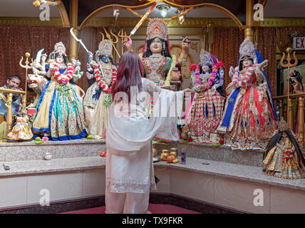 Une femme hindoue effectue le rituel de l'aarti offrant la lumière et flammes aux déités. Dans un temple à Ozone Park, Queens, New York. Banque D'Images