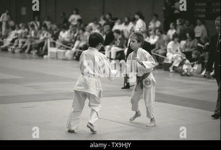 Années 1980, historiques, deux jeunes garçons Vêtements de coton blanc dans la compétition sur un mat à un événement judo, England, UK. L'art martial a été créé au Japon en 1882 comme un exercice mental et physique par son fondateur Jigoro Kano et est maintenant un sport olympique ayant été démontré lors de la 1932 de 2010. Pourtant, son fondateur Kano était ambivalent à ce sujet, car il croyait que le Judo a été beaucoup plus qu'un simple sport, d'être un moyen de réalisation culturelle personnelle, Banque D'Images