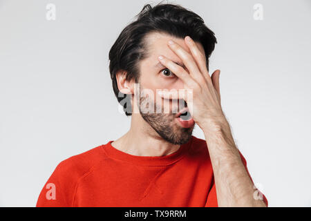 Beau jeune homme choqué barbu brunette wearing sweater isolés sur fond blanc, couvrir les yeux Banque D'Images