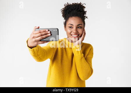 Image libre de cute african american woman looking at smartphone et smiling isolated over white background Banque D'Images
