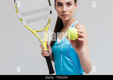 Portrait d'un joueur de tennis woman holding racket et isolé sur fond gris à billes Banque D'Images