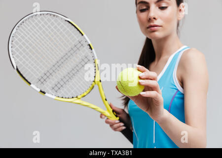 Portrait d'un joueur de tennis woman holding racket et isolé sur fond gris à billes Banque D'Images