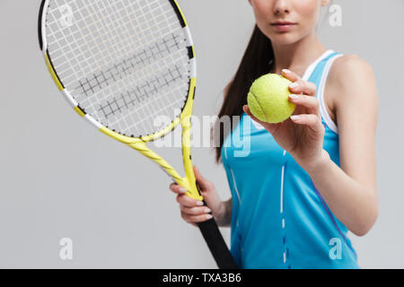 Portrait d'un joueur de tennis woman holding racket et isolé sur fond gris à billes Banque D'Images