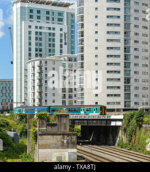 CARDIFF, WALES - Juin 2019 : Commuter train sur le réseau des lignes de la vallée de traverser un pont en face de l'appartement des bâtiments et le Radisson Blu Hotel Banque D'Images