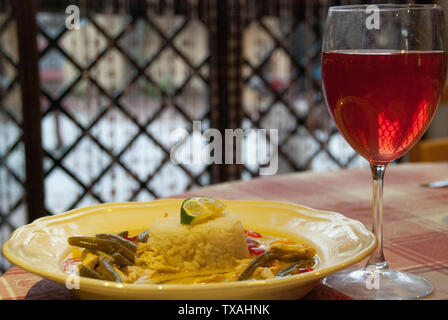 La nourriture typique asiatique avec du riz blanc et curry avec du lait de coco et crème épicé servi avec des légumes et le vin rouge Banque D'Images