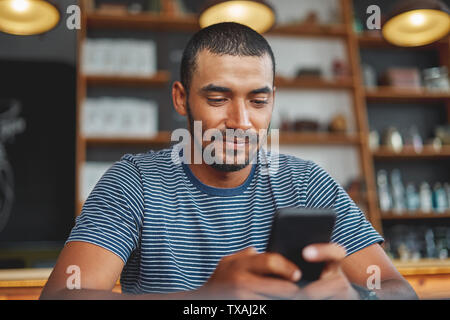 Jeune homme à l'aide de café en smartphone Banque D'Images