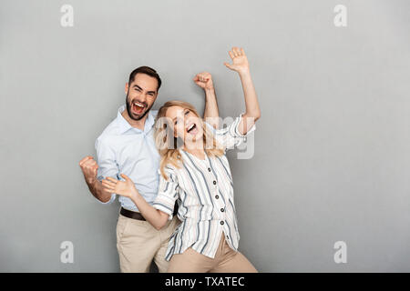 Gros plan photo de couple en habits de sourire et de célébrer la réussite de mur gris plus isolés Banque D'Images