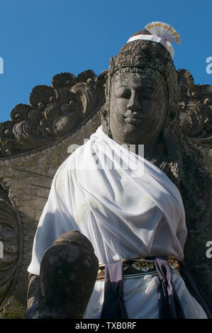 Photo d'une belle statue de Bouddha en pierre habillé avec une corde blanche et situé sur la route principale à Ubud, Bali - Indonésie Banque D'Images