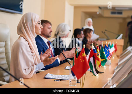 Les jeunes filles en hijab délégué et ses collègues étrangers applaudir Banque D'Images