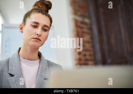 Head and shoulders portrait of young businessman standing contemporain tout en travaillant au tableau de l'office, copy space Banque D'Images