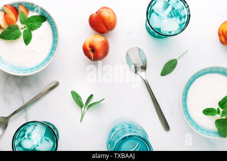 Vue de dessus du petit déjeuner sain de yaourt grec naturel, nectarines et de l'eau sur table de marbre. Mise à plat. Banque D'Images