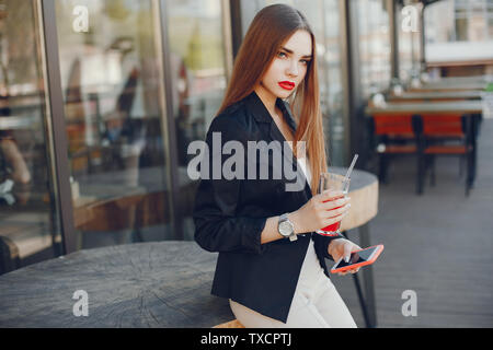 Femme élégante dans un café. Dame au téléphone. Fille à la mode dans une veste noire. Mort a boire un jus de fruits Banque D'Images