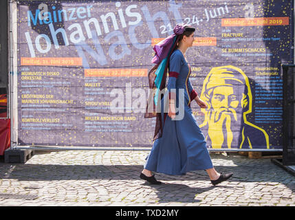 Mainz, Allemagne. 22 Juin, 2019. Lea Kemper, Gutenberg Foundation, passe devant un bandeau publicitaire pour Johannisnacht dans une forme contemporaine. Des centaines de milliers de personnes sont attendues dans les rues et places entre Schillerplatz et les rives du Rhin au cours de Mayence Johannisnacht 2019. Crédit : Andreas Arnold/dpa/Alamy Live News Banque D'Images