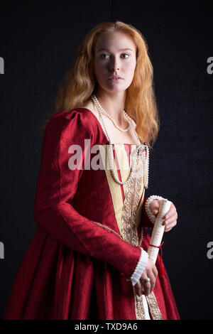 Femme Tudor en robe rouge sur fond noir Banque D'Images