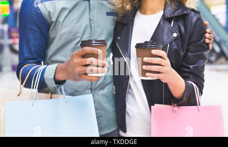 Méconnaissable african couple drinking coffee pour aller après de longues shopping piscine, panorama Banque D'Images