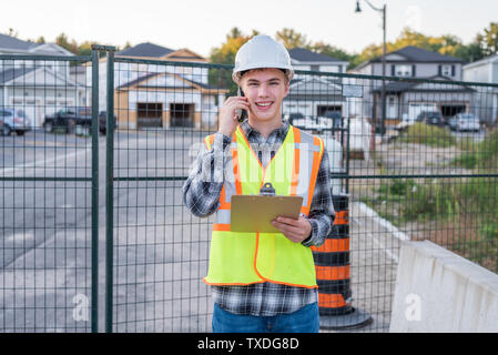 Happy construction foreman parle avec un employé sur son téléphone cellulaire. Banque D'Images