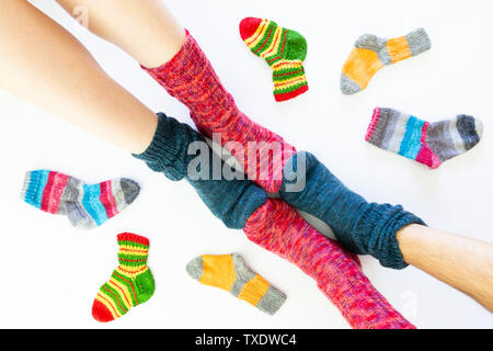 Vue de dessus d'un assortiment de chaussettes de laine de différentes tailles sur fond blanc avec deux paires de pieds portant une chaussette rouge et bleu Banque D'Images