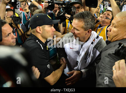 Ohio State Buckeyes urbain entraîneur-chef Meyer (R), serre la main avec l'Oregon Ducks entraîneur en chef Mark Helfrich après les Buckeyes défait les Oregon Ducks 42-20 pour gagner le match de Football Championnat National, à Arlington, au Texas le 12 janvier 2015. Photo par Kevin Dietsch/UPI Banque D'Images