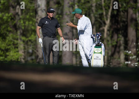 Phil Mickelson parle à sa caddie Jim Mackay, qui attendent pour frapper sur le 11ème fairway pendant le premier tour de la 2014 tournoi Masters à Augusta National Golf Club à Augusta, Géorgie, le 10 avril 2014. UPI/Kevin Dietsch Banque D'Images