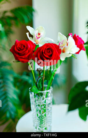 Bon bouquet de roses rouges et orchidées blanches dans un vase isolé sur fond blanc Banque D'Images