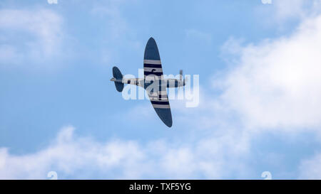 Weston-super-Mare, Royaume-Uni. 22 Juin, 2019. Battle of Britain Memorial Flight avec un dessous Vue d'un avion Spitfire vintage, isolés ici en plein vol à l'air Festival 2019 Weston, voler haut dans le ciel bleu d'été, à travers la lumière nuages sur Weston-super-Mare du littoral canadien. Credit : Hudson Lee Banque D'Images