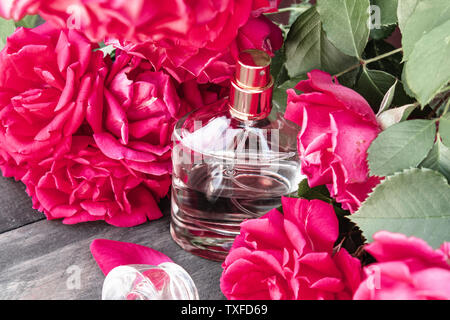 Flacon de parfum entouré de roses rouges. L'Aromathérapie Banque D'Images