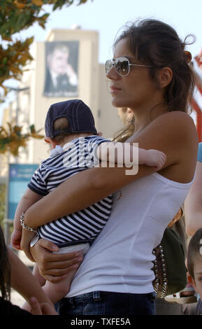 Un australien avec son enfant en attente d'être évacués dans le centre de Beyrouth en dessous d'un portrait de l'ancien Premier ministre libanais Rafic Hariri le 19 juillet 2006. Des dizaines de milliers de ressortissants étrangers se préparent pour l'évacuation du Liban au cours des prochains jours. Certains partent en bus convois à travers la Syrie tandis que d'autres prennent les transbordeurs à Chypre. Plus de 300 Libanais, pour la plupart des civils, ont péri depuis le début du conflit le 12 juillet, après que le Hezbollah guérilleros kidnappé deux soldats israéliens tués et 7 autres. UPI (photo) Banque D'Images