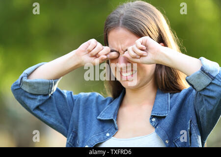 Femme souffrant de démangeaisons se gratter les yeux à l'extérieur dans un parc Banque D'Images