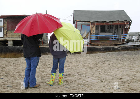 Deux personnes sous les parasols stop pour inspecter des cottages qui ont été endommagés par l'Ouragan Sandy de tempête au Roy Carpenter Beach à South Kingstown, Rhode Island le 30 octobre 2012. Le salon a été l'un des plus durement touchés par la tempête de l'Ouragan Sandy. UPI/Matthew Healey Banque D'Images